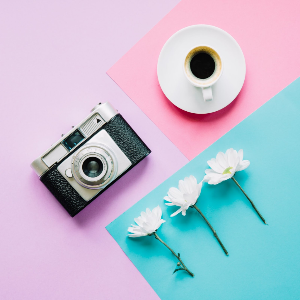 A camera, a cup of coffee, and three white flowers