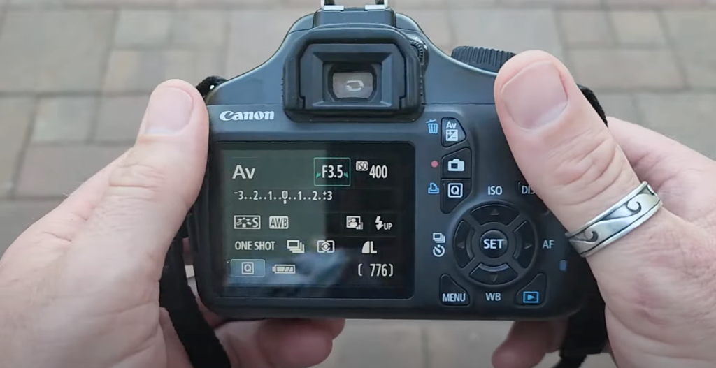 Hands holding a black camera, making adjustments to its settings and features.