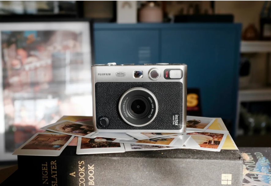 A Polaroid camera with several photos on a book