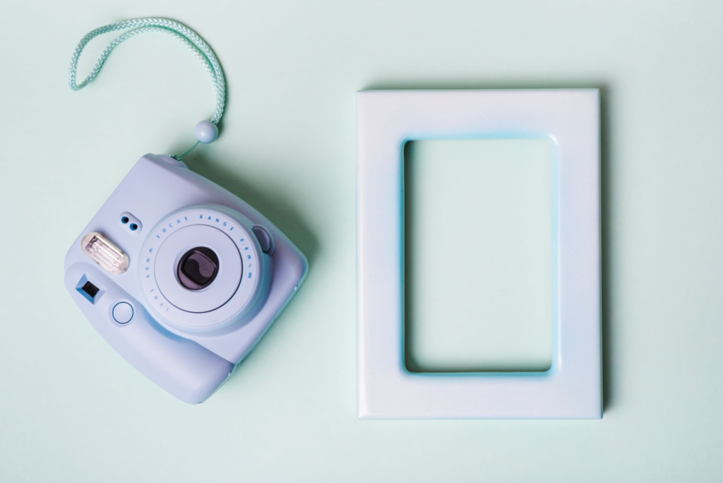 a turquoise Instax Mini 11 camera with a string and a picture frame 