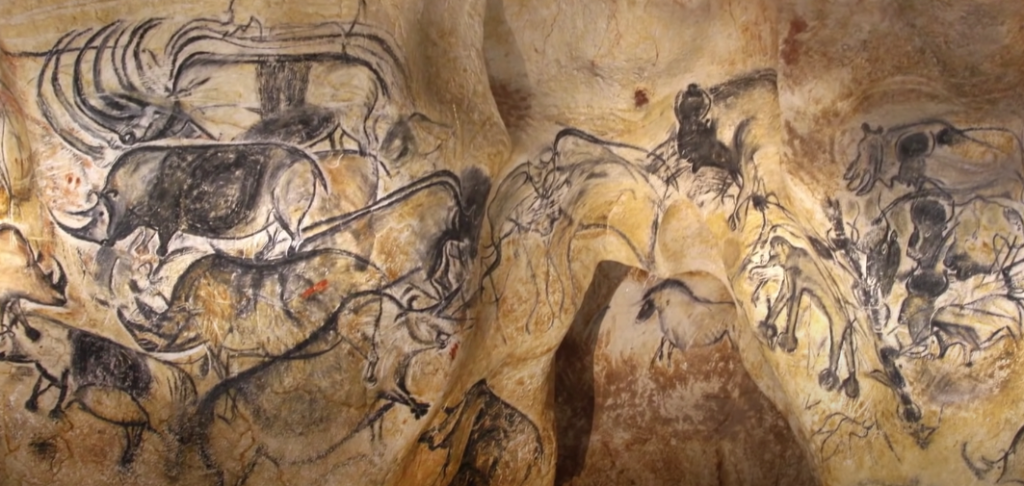 Photograph capturing cave paintings featuring various animals such as cows, bulls, and oxen.